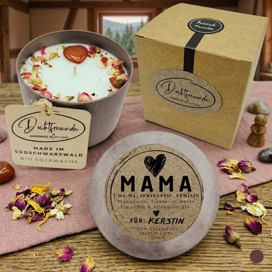 Eine personalisierte Sojawachs-Kerze im Betongefäß für Mama, handgefertigt im Schwarzwald. Zu sehen ist die Kerze mit Trockenblumen und Edelstein-Herz, die passende Kraftpapier-Geschenkbox und ein personalisierter Deckel mit der Aufschrift „MAMA Definition“ und dem Wunschnamen „Kerstin“.